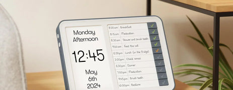 Relish Day Hub dementia clock on a living room side table showing Monday Afternoon and a task list