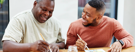 A father and son are enjoying painting, which is a great activity for seniors to do alone or as a group activity.