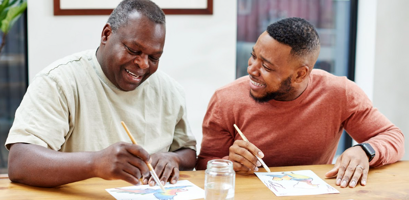 A father and son are enjoying painting, which is a great activity for seniors to do alone or as a group activity.