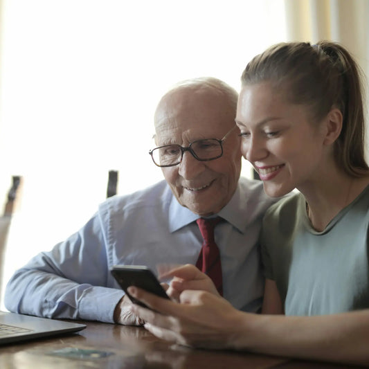 A lovely image of an elderly man and his daughter browsing Dementia Black Friday deals on their phone.