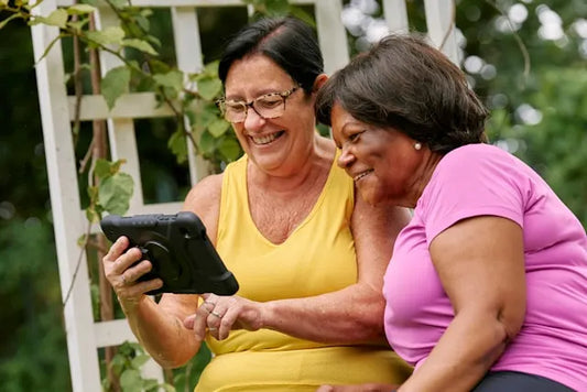 two senior women looking at dementia apps on a tablet and smiling