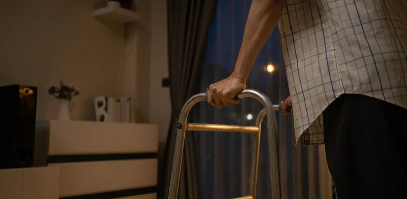 An elderly person gripping a walker in a dark room, illustrating nighttime dementia wandering