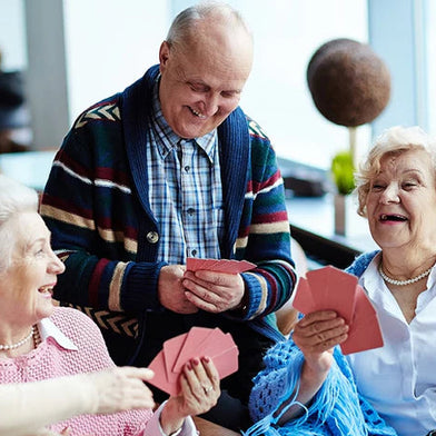 Three older friends enjoying a card game together, a sociable summer activity for people with dementia