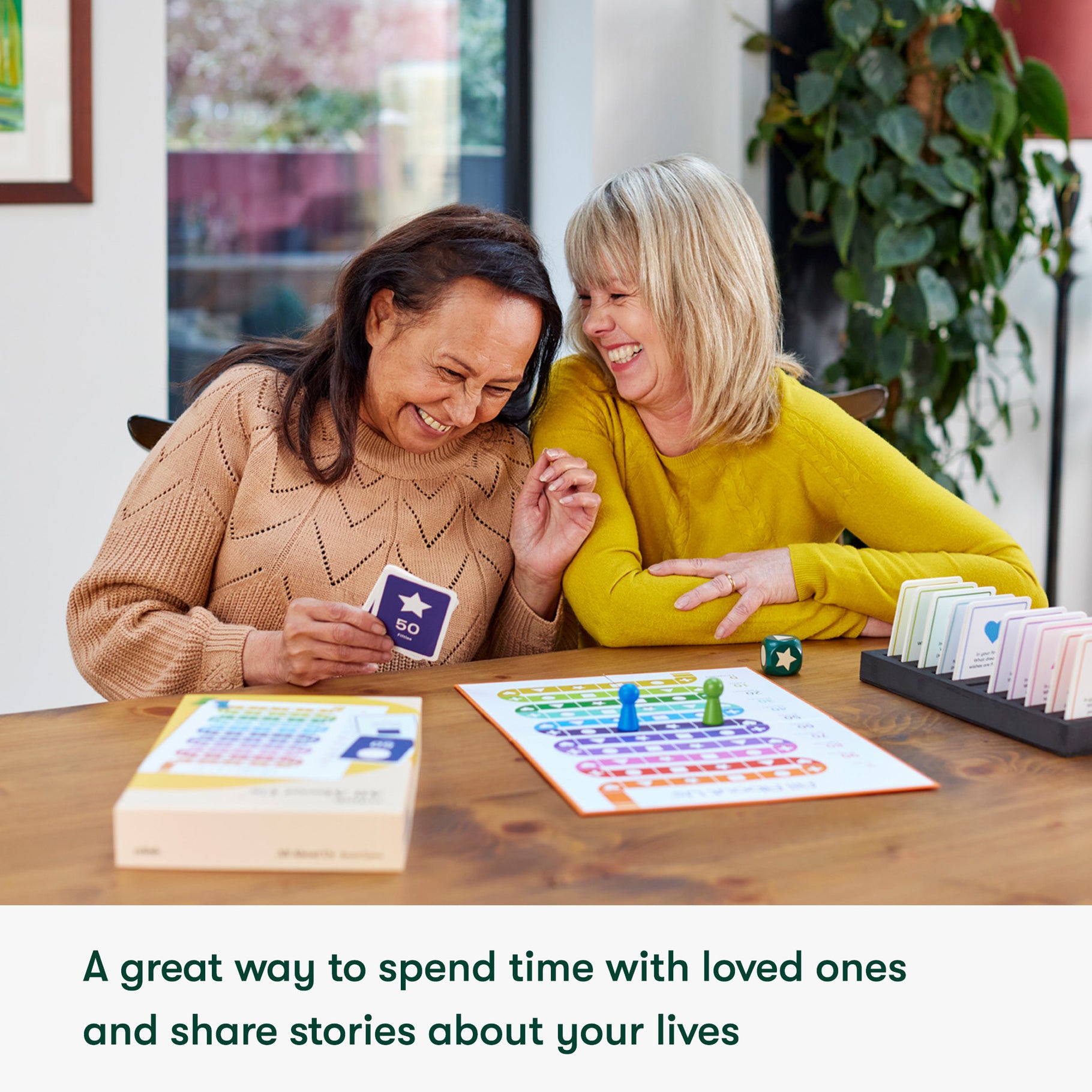Two women play a board game together, sharing a joyful moment.