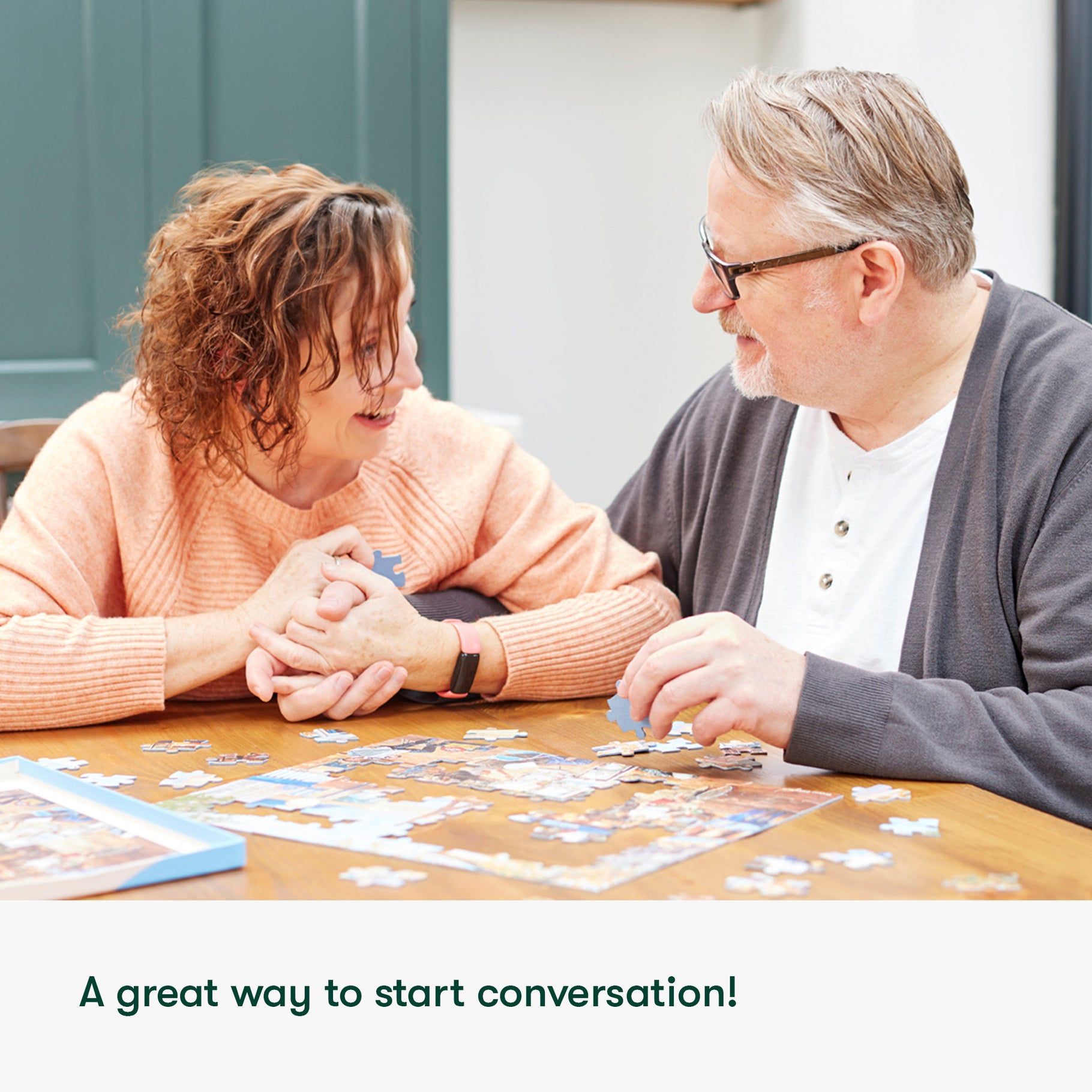 A smiling couple is assembling a puzzle together, promoting engagement for people with dementia.