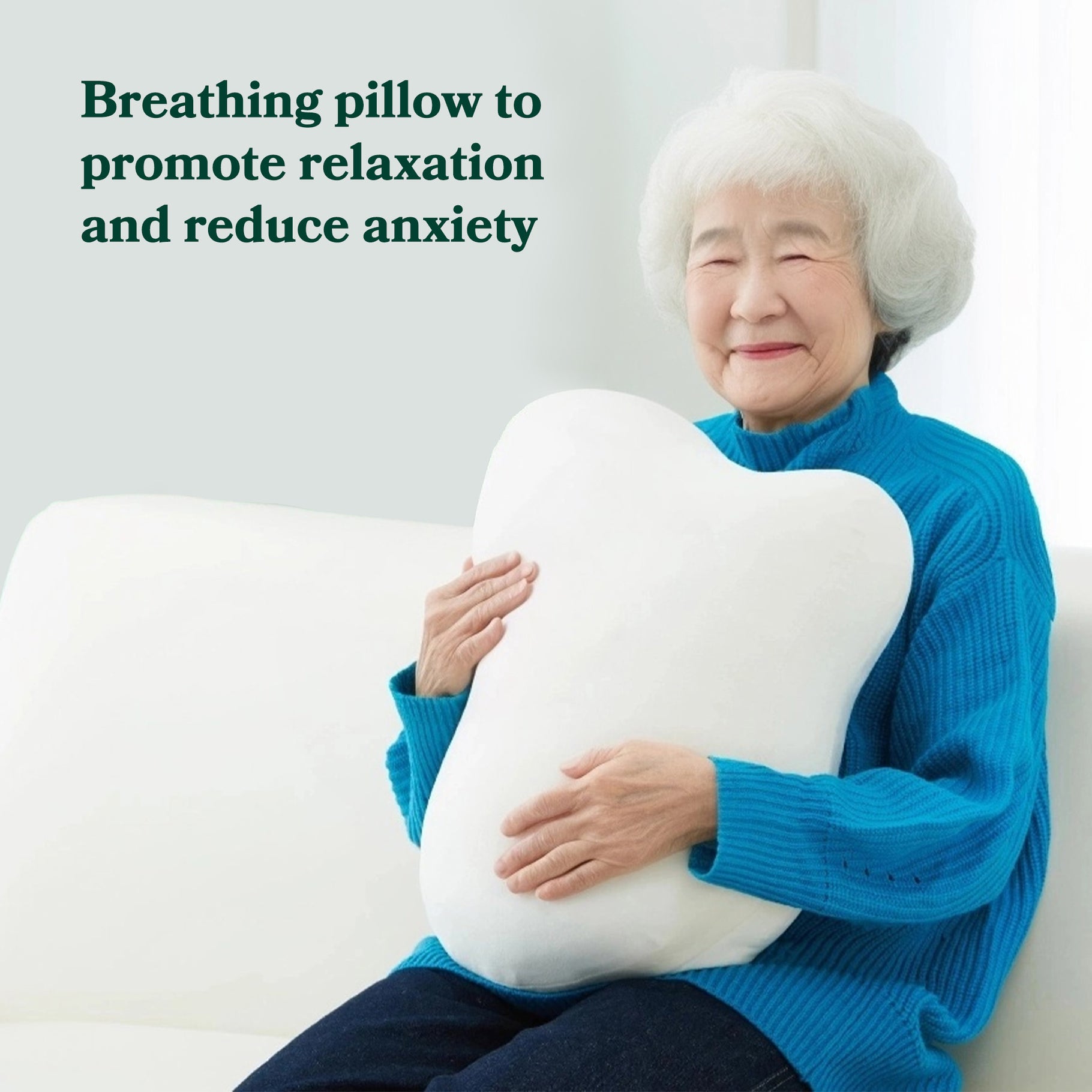 An older women sat calming on the sofa, embracing and hugging the Fufuly calming cushion. Image caption: Breathing pillow to promoting relaxation and reducing anxiety.