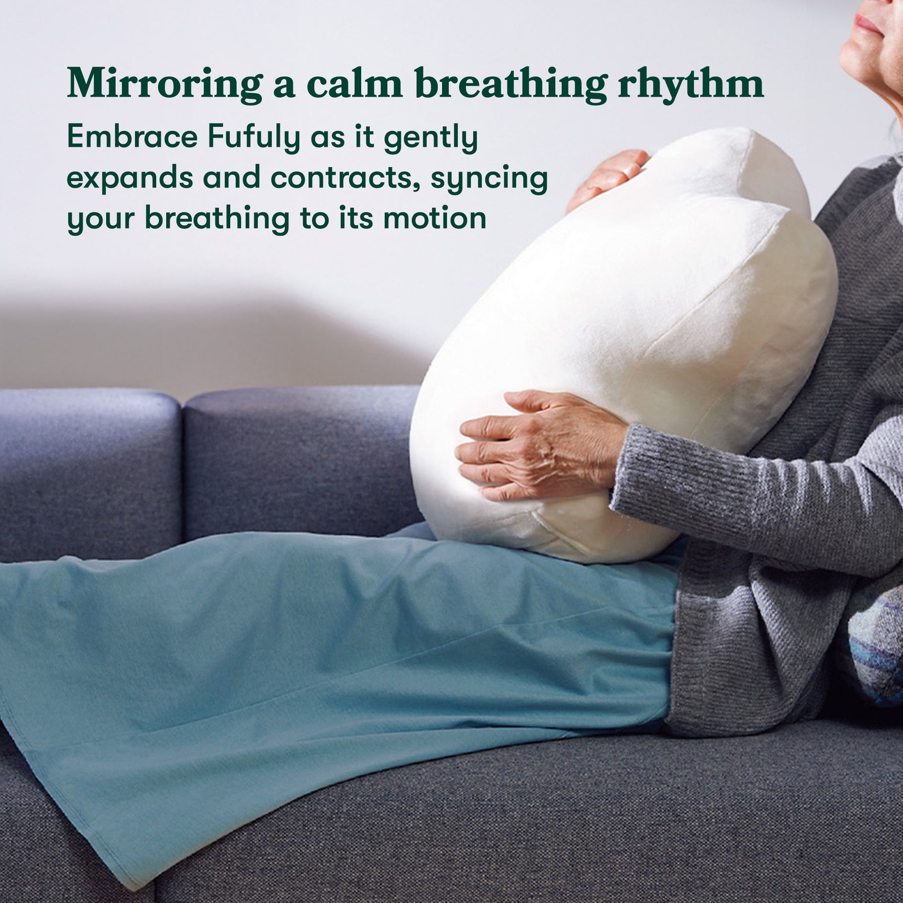 Women sat holding Fufuly calming cushion. Image caption: Mirroring a calm breathing rhythm. Embrace Fufuly as it gently expands and contracts, syncing your breathing to its motion.