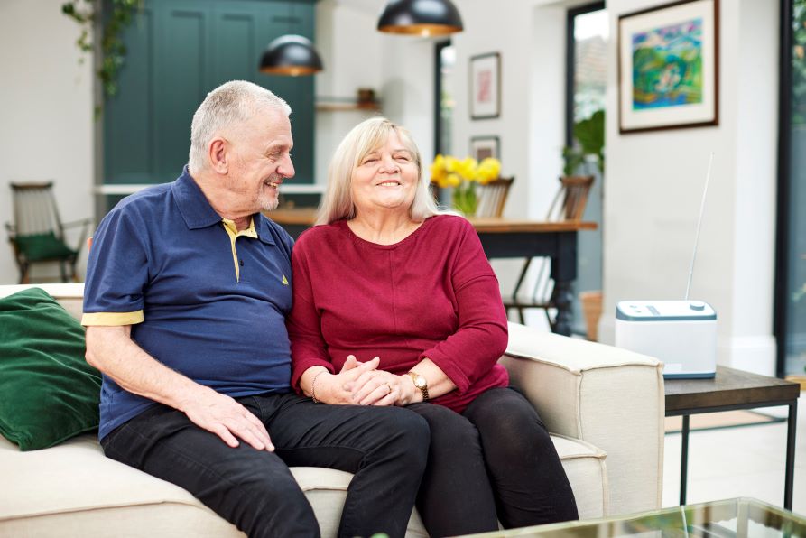 A couple sat on sofa listening to a Relish Radio