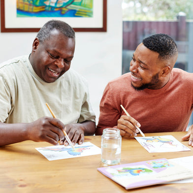 Two people smiling while painting together, fostering creativity and connection.