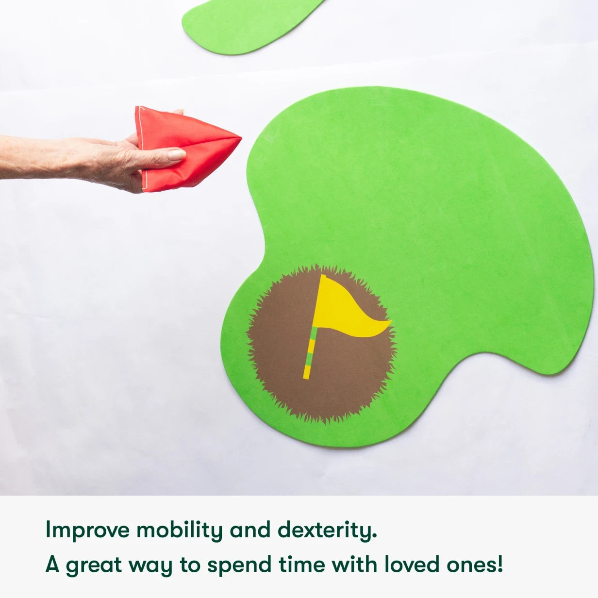 Elderly hand tosses beanbag onto green target, promoting activities for people living with dementia and care home residents.