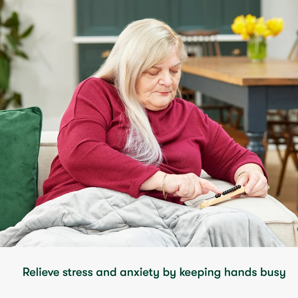 A woman uses a tactile activity to relieve stress, sitting comfortably on a couch.