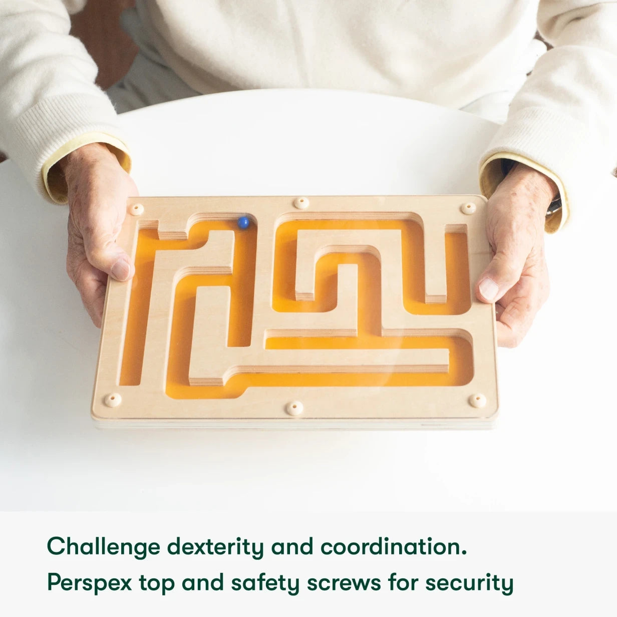 Elderly hands hold a wooden maze, ideal for dementia activities, enhancing dexterity and coordination in care homes.