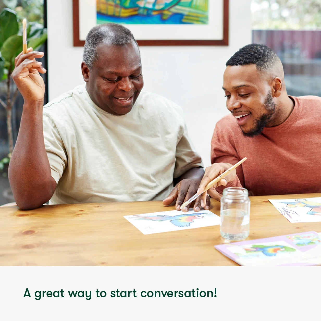 Elderly man and young man enjoy aqua painting for dementia, a perfect activity for care homes, fostering joy and connection.