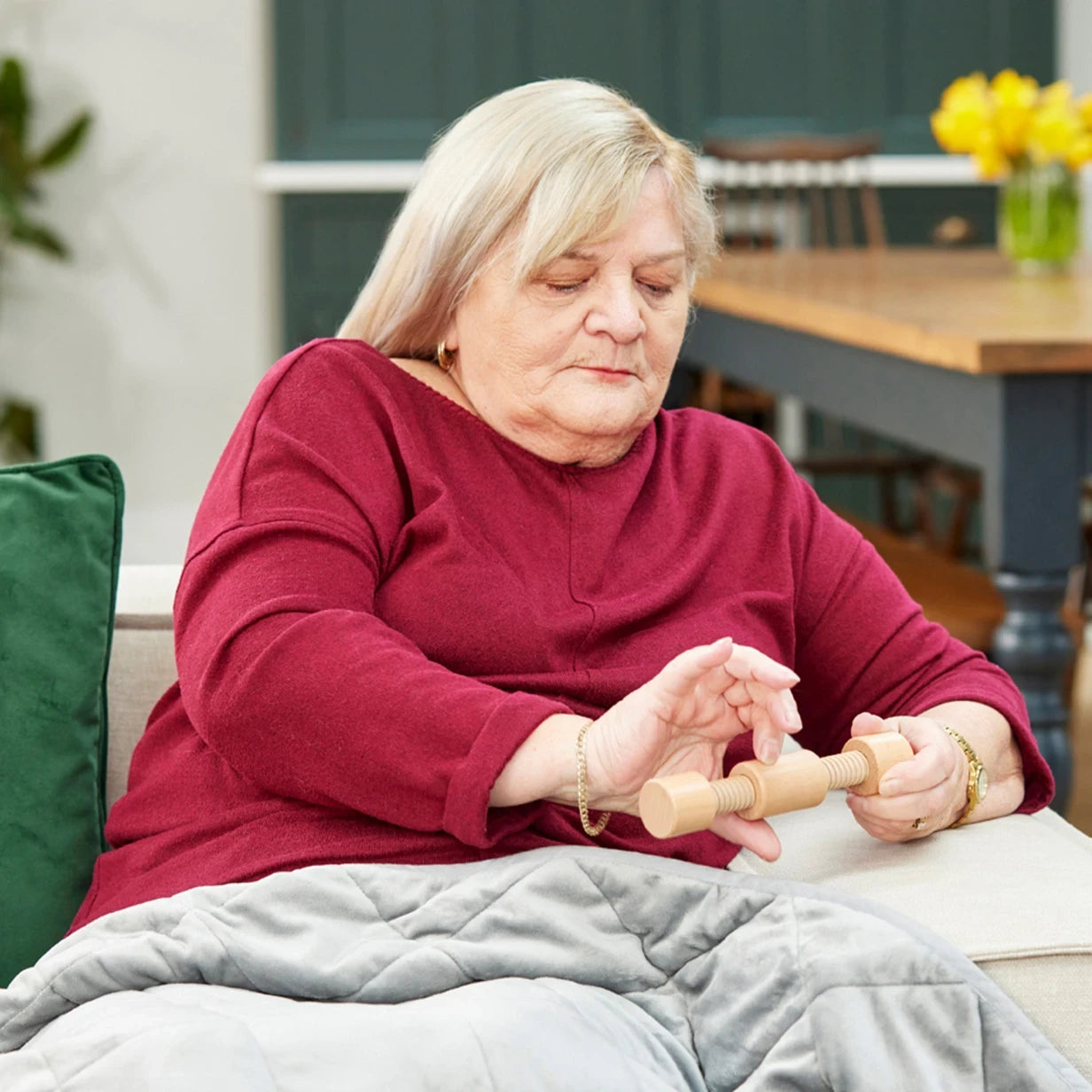 Elderly woman using a fidget toy, ideal for dementia activities in care homes, promoting calm and engagement for seniors.