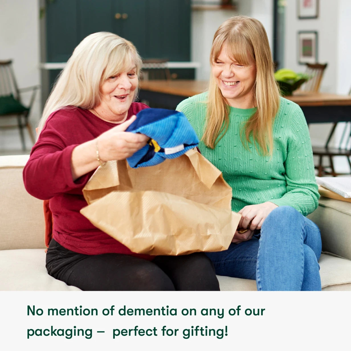 Two women smiling, opening a gift bag with dementia-friendly products. Ideal for care home activities and Alzheimer's gifts.